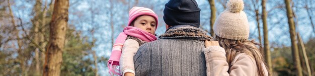 Vue arrière du couple avec sa petite fille profitant ensemble du paysage forestier. Concept de temps libre en famille.