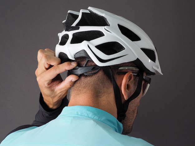 Vue arrière du cycliste masculin ajuste la taille du casque.