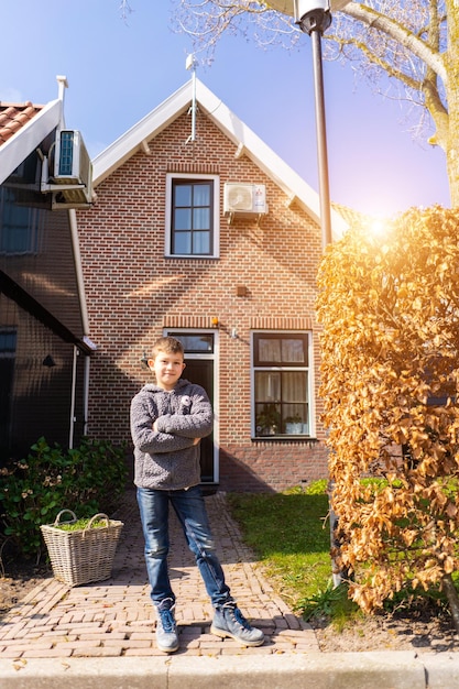 Vue arrière du garçon heureux se tient près de leur maison moderne Petit garçon se tient près de la maison