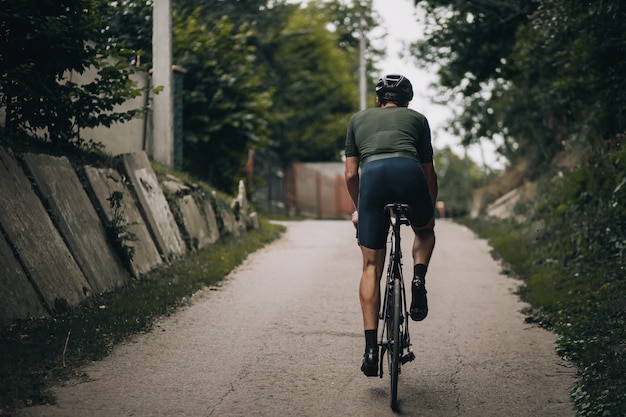 Vue arrière du gars musclé pratiquant le cyclisme en plein air