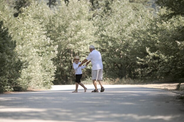 Vue arrière du grand-père et du petit-fils avec chapeau marchant sur la nature