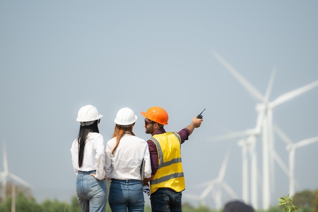 Vue arrière du groupe d'ingénieurs et d'architectes sur un chantier de construction avec des éoliennes en arrière-plan