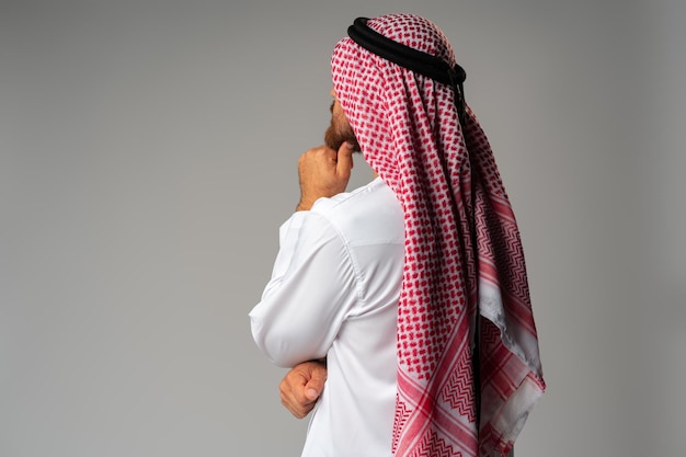 Vue arrière du jeune homme arabe debout sur fond gris