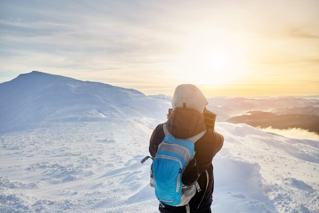 Vue arrière du jeune homme faisant la photo des montagnes d'hiver