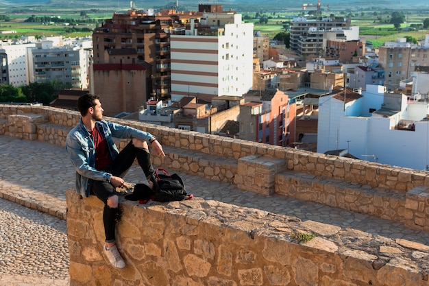 Vue arrière du jeune homme regardant la ville depuis le toit du château. Concept de mode de vie et de liberté.