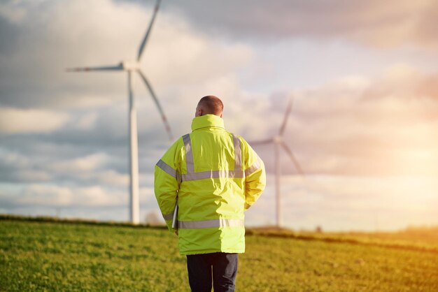 Vue arrière du jeune ingénieur masculin dans une ferme éolienne en arrière-plan