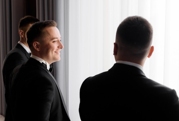 Vue arrière du marié et de ses amis attendent la cérémonie de mariage dans la chambre d'hôtel