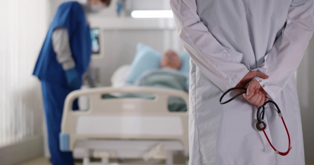 Vue arrière du médecin tenant un stéthoscope debout dans la salle d'hôpital