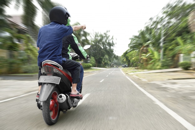 Vue arrière du passager indiquant le chemin au chauffeur de taxi moto