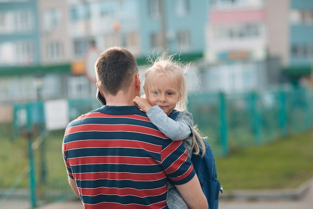 Vue arrière du père retournant à l'école avec sa petite fille.