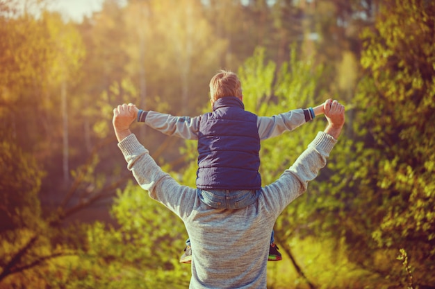 Vue arrière du père de son fils sur les épaules de la nature.