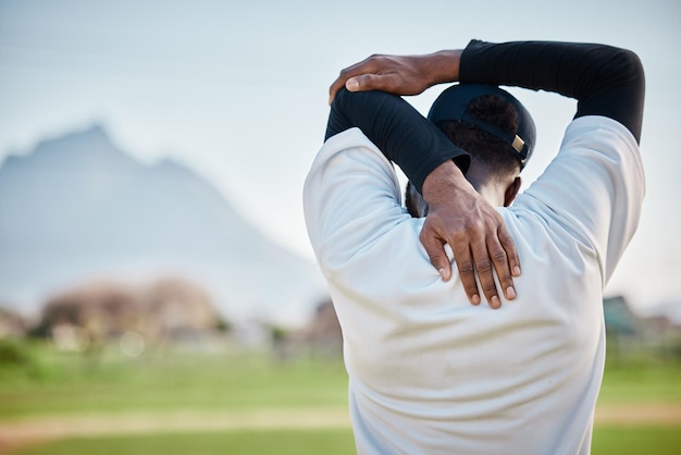 Vue arrière du terrain de baseball ou homme noir qui s'étend en s'entraînant prêt pour le match sur le terrain en été