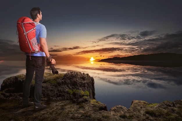 Vue arrière du touriste asiatique homme avec appareil photo et sac à dos en regardant la vue du coucher de soleil