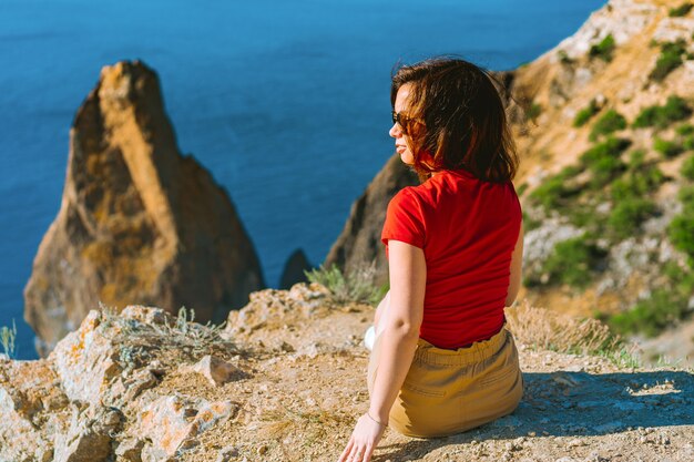 Photo vue arrière du voyageur femme debout sur le bord de la falaise en face de l'incroyable paysage marin, concept de voyage.