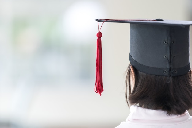 Photo vue arrière les écolières asiatiques diplômées avec un chapeau de graduation détiennent un certificat roulé. concept de célébration de remise des diplômes banque de photo