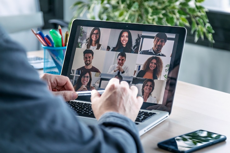 Photo vue arrière d'un employé masculin parlant en appel vidéo avec divers collègues lors d'un briefing en ligne avec un ordinateur portable à la maison.