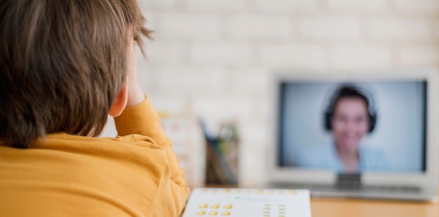 Photo vue arrière d'un enfant instruit à la maison grâce à un cours en ligne