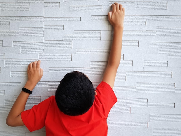 Photo vue arrière d'un enfant en vêtements décontractés grimpant sur le mur