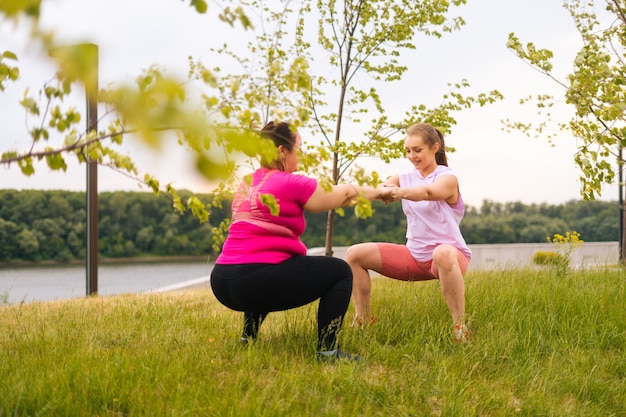 Vue arrière de l'entraîneur féminin professionnel de remise en forme donnant une formation personnelle à une jeune femme en surpoids