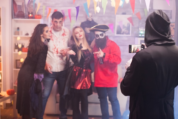 Vue arrière de la faucheuse prenant une photo d'amis à la fête d'halloween.