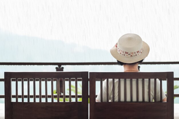 Vue arrière de la femme d'âge moyen sur un banc en jour de pluie