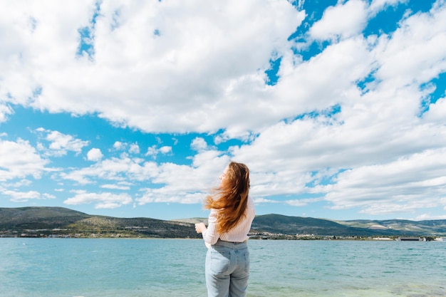 Vue arrière de la femme appréciant la vue sur l'océan avec des montagnes