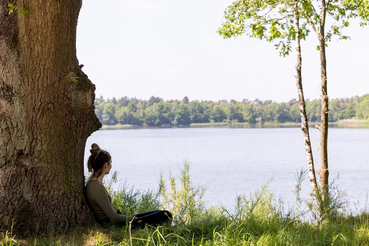 Photo vue arrière d'une femme assise au bord d'un lac