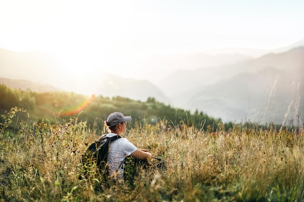 Vue arrière d'une femme assise sur un champ contre une montagne