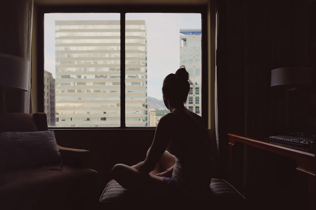 Vue arrière d'une femme assise dans une chambre d'hôtel