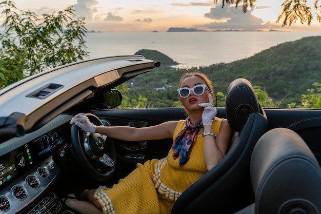 Vue arrière d'une femme assise dans une voiture contre le coucher du soleil
