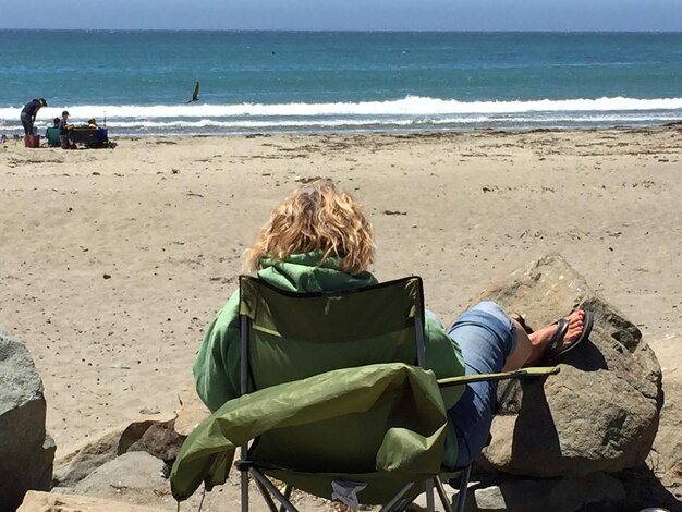 Vue arrière d'une femme assise sur la plage