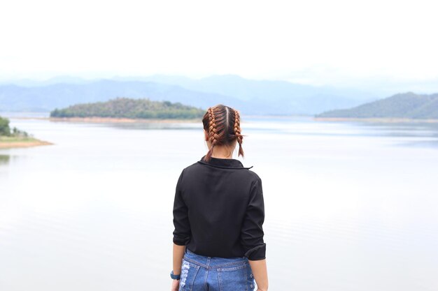 Photo vue arrière d'une femme aux cheveux tressés debout au lac