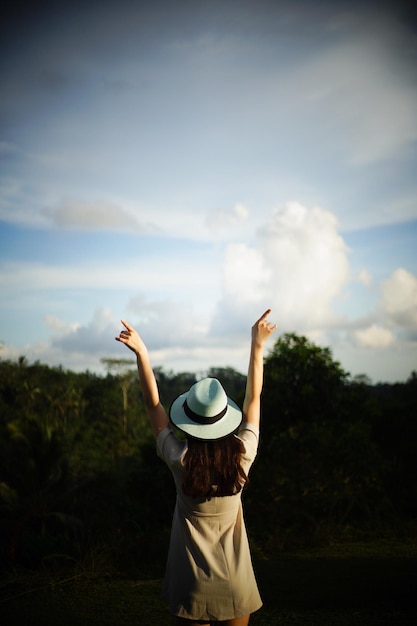 Vue arrière d'une femme avec les bras levés alors qu'elle se tient contre le ciel