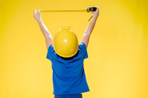 Vue arrière d'une femme avec les bras levés debout contre un mur jaune