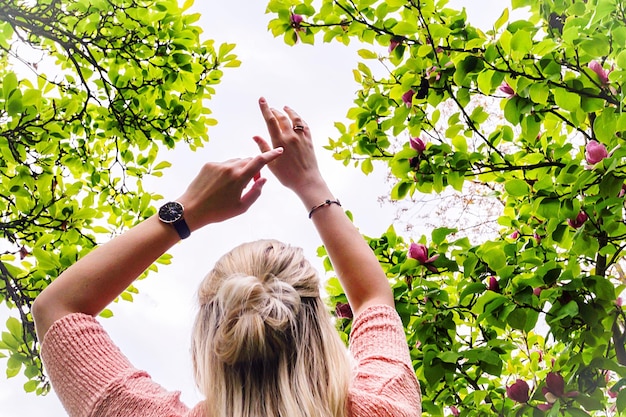 Photo vue arrière d'une femme avec les bras levés debout près des arbres