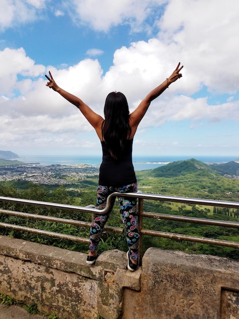 Photo vue arrière d'une femme avec les bras levés vers le ciel