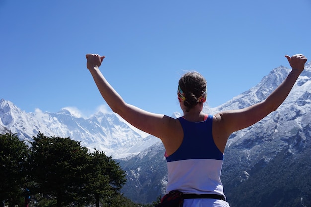 Photo vue arrière d'une femme avec les bras tendus debout contre la montagne