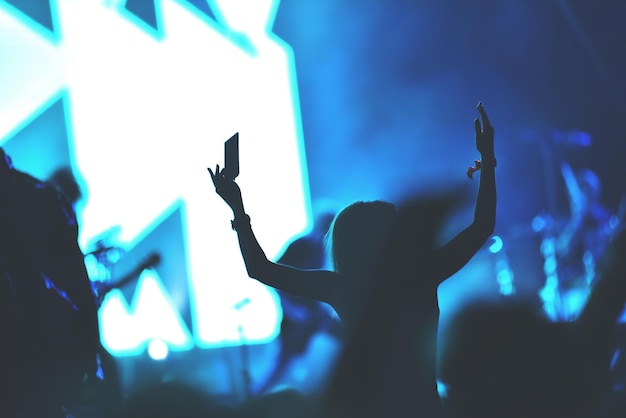 Vue arrière d'une femme avec les bras tendus lors d'un concert