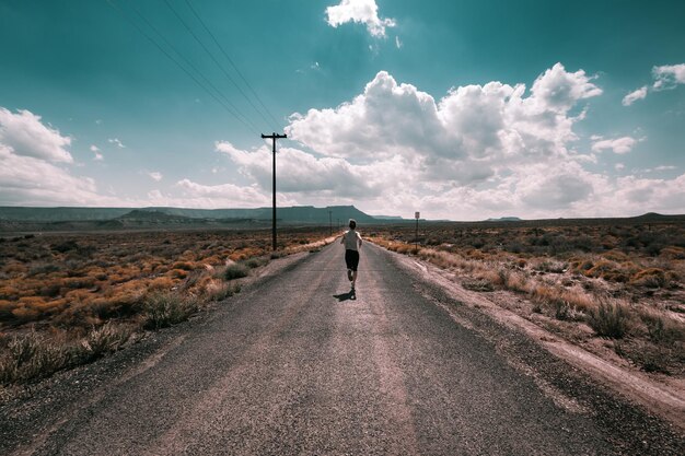 Photo vue arrière d'une femme courant sur la route contre le ciel