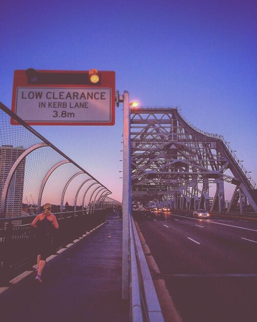 Photo vue arrière d'une femme courant sur le sentier sur le pont contre le ciel