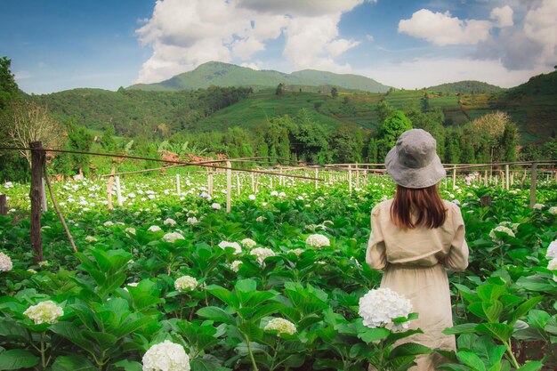 Photo vue arrière d'une femme debout au milieu des plantes à fleurs à la ferme