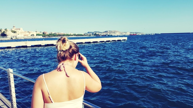 Vue arrière d'une femme debout sur un bateau en mer contre un ciel clair