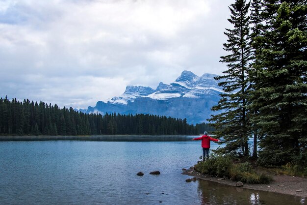 Photo vue arrière d'une femme debout avec les bras tendus par le lac pendant l'hiver