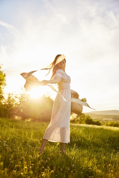 Vue arrière d'une femme debout sur un champ contre le ciel au coucher du soleil