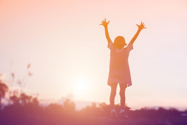 Vue arrière d'une femme debout sur un champ contre le ciel au coucher du soleil