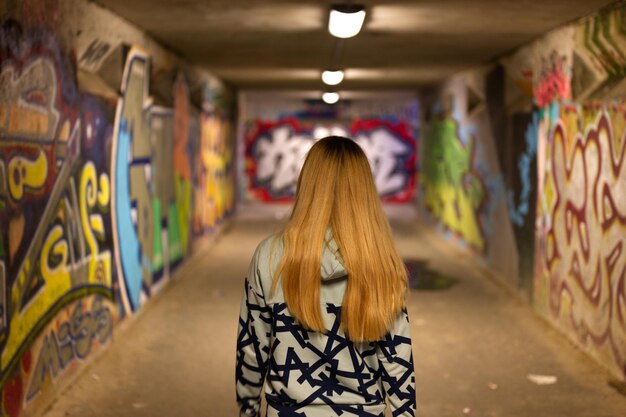 Photo vue arrière d'une femme debout contre des graffitis