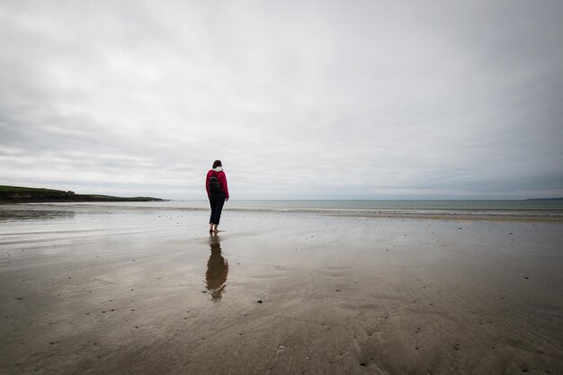Vue arrière d'une femme debout sur la plage contre le ciel