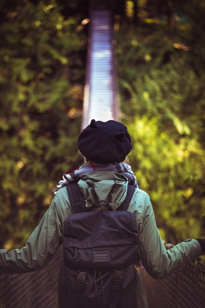 Photo vue arrière d'une femme debout sur un pont piétonnier dans la forêt