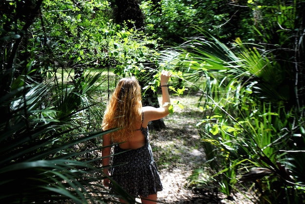 Photo vue arrière d'une femme debout près des plantes dans la forêt