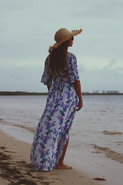 Photo vue arrière d'une femme debout sur le rivage à la plage contre le ciel